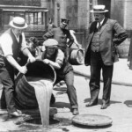 John Leach, the New York City Deputy Police Commissioner, stands by as agents pour bootleg liquor into the sewer. Police raids could barely keep up with the flow of illegal alcohol during Prohibition.